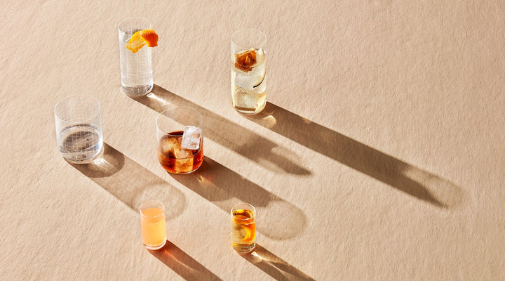 NUDE Finesse collection, a range of simple minimalistic whisky and longdrink glasses presented on a beige surface and a play with shadows