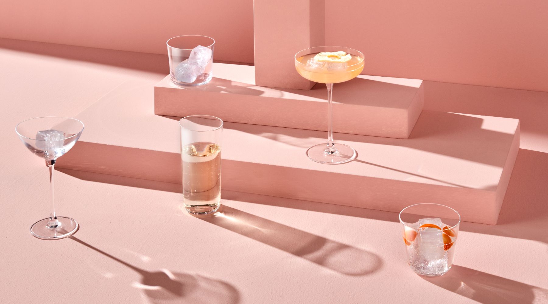 NUDE Savage collection - range of mixology glasses such as coupe, pony, coupetini and highball and lowball presented with pink coloured cocktails