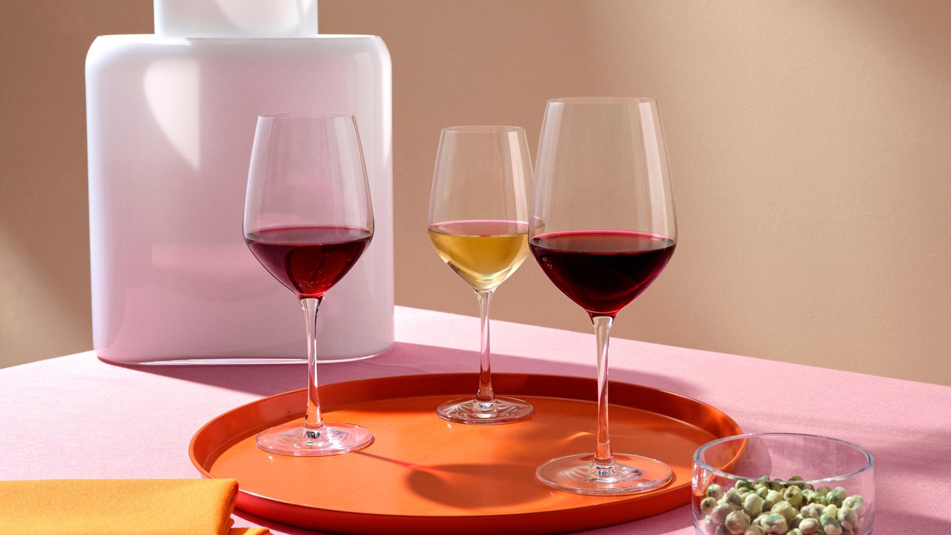 NUDE Climats red wine, white wine and light red wine glasses on an orange tray with Layers vase and Malt Bowl on a pink table