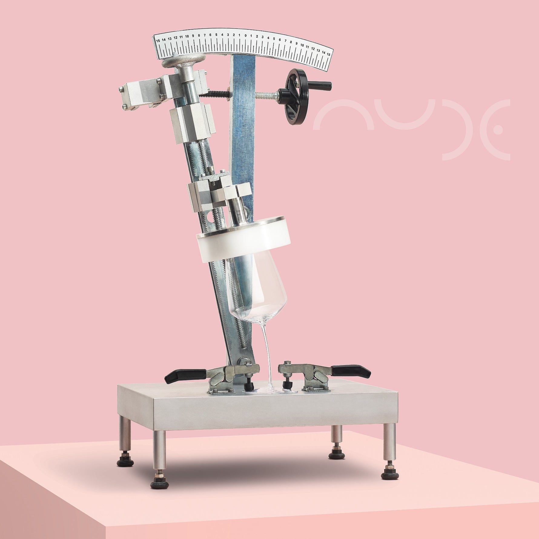 Mechanical device testing the bendability of a glass on a pink platform with NUDE logo
