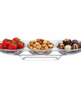 Clear glass appetizer tray with strawberries, nuts, and chocolates on a white background