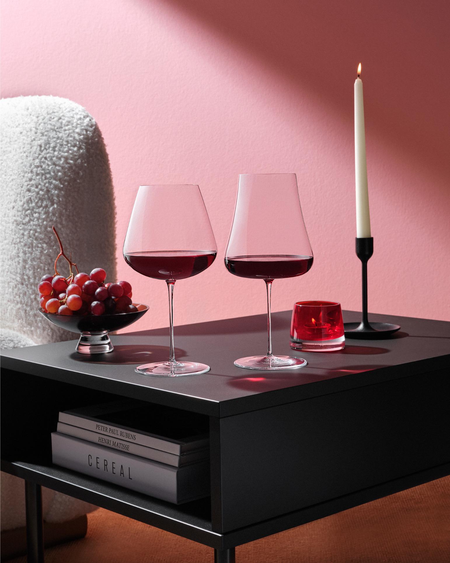 NUDE Stem Zero Volcano and Elegant red wine glasses on a dark coffee table with grapes, red votive and candlelight