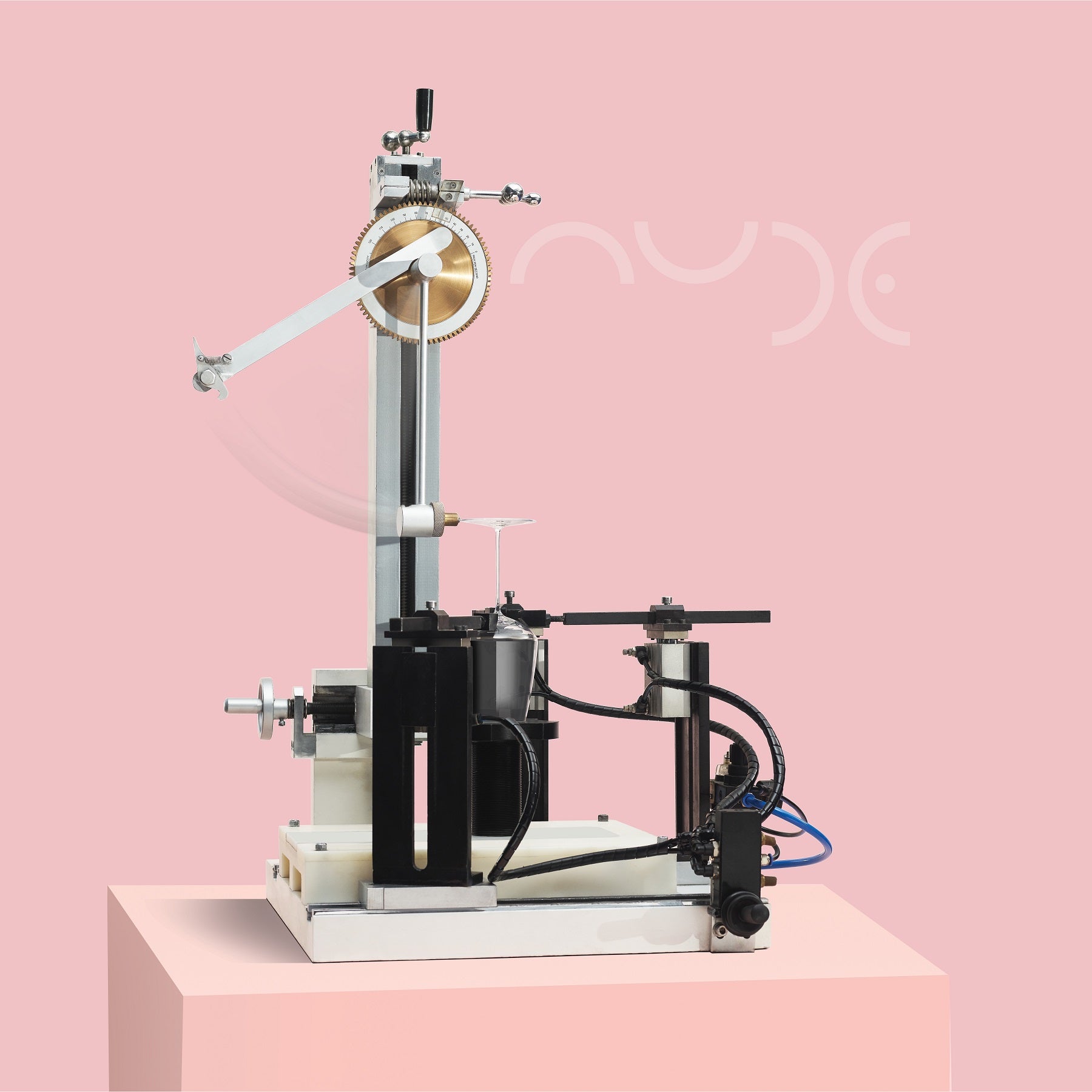 Mechanical device testing the stem impact of a glass on a pink background with 'Nude' branding.