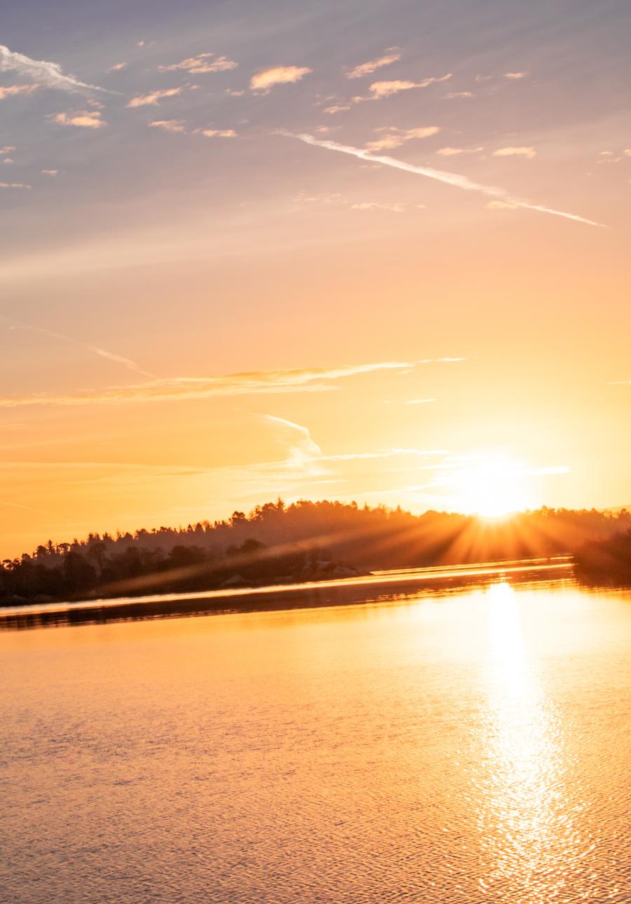 Sunset over a body of water with a city skyline in the distance.