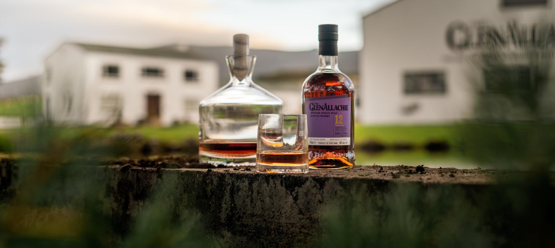 NUDE Alba Collection decanter and whisky glass with GlenAllachie 12 Year Speyside Single Malt Scotch Whisky in front of the GlenAllachie distillery, photography by Murray Anderson