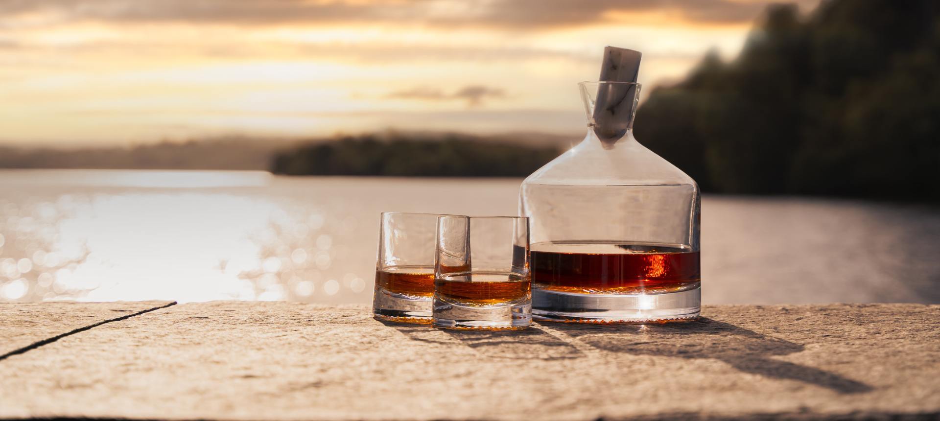 NUDE Alba Collection decanter and whisky glasses by Joe Doucet on a loch shore at sunset, photography by Murray Anderson