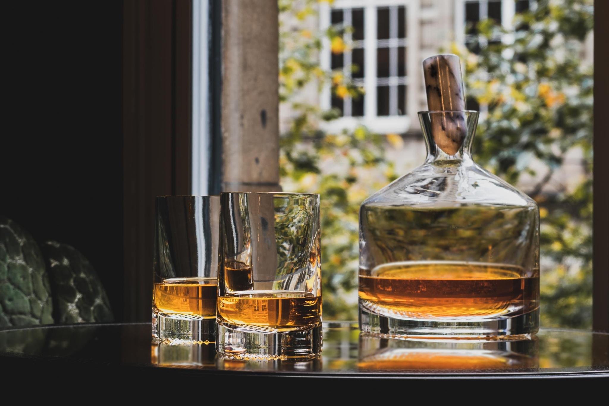 NUDE Alba whisky glasses and carafe on a table by a window overlooking a garden
