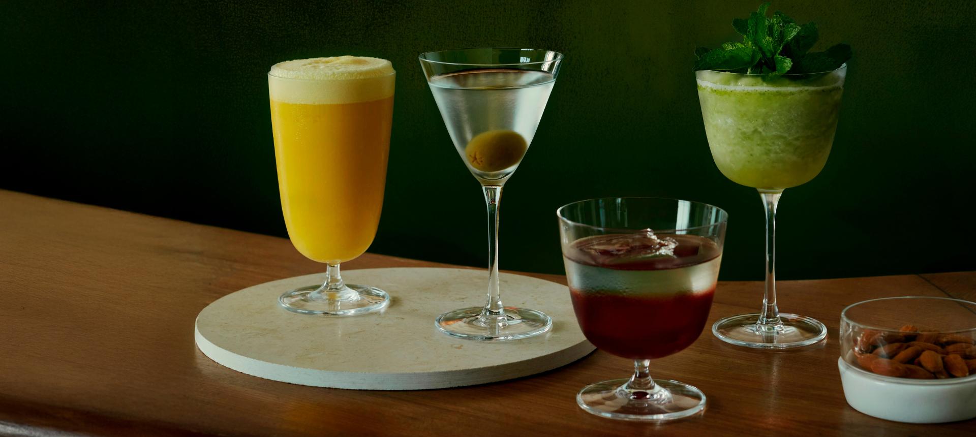 The NUDE Bar/Giani collection lined up on a bar: Cocktail Glass Short, Cocktail Glass Long Stem, Cocktail Glass Long and Martini Glass, with a chill bowl