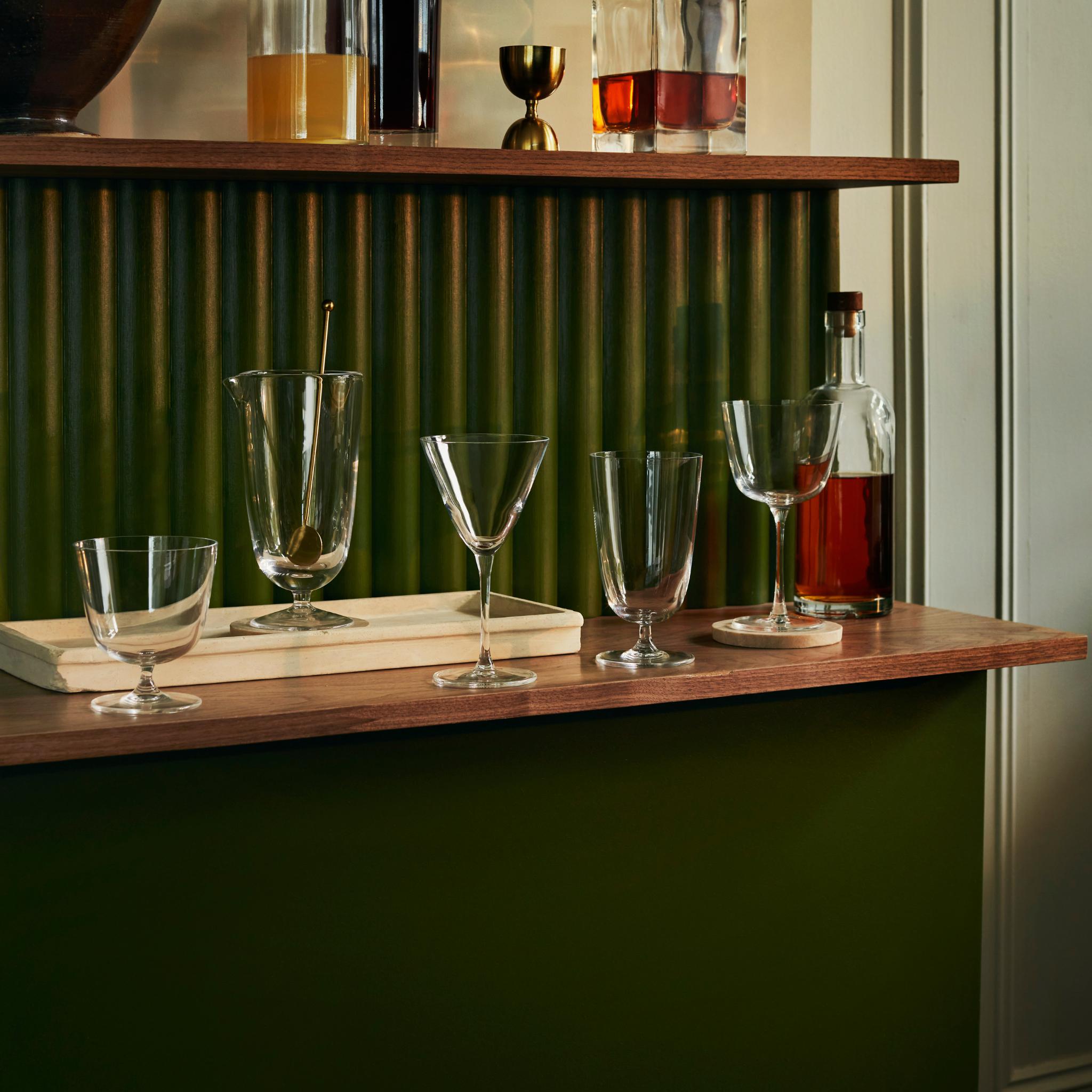 NUDE Bar/Giani glasses on a home bar shelf, including the Mixing Glass with a bar spoon.