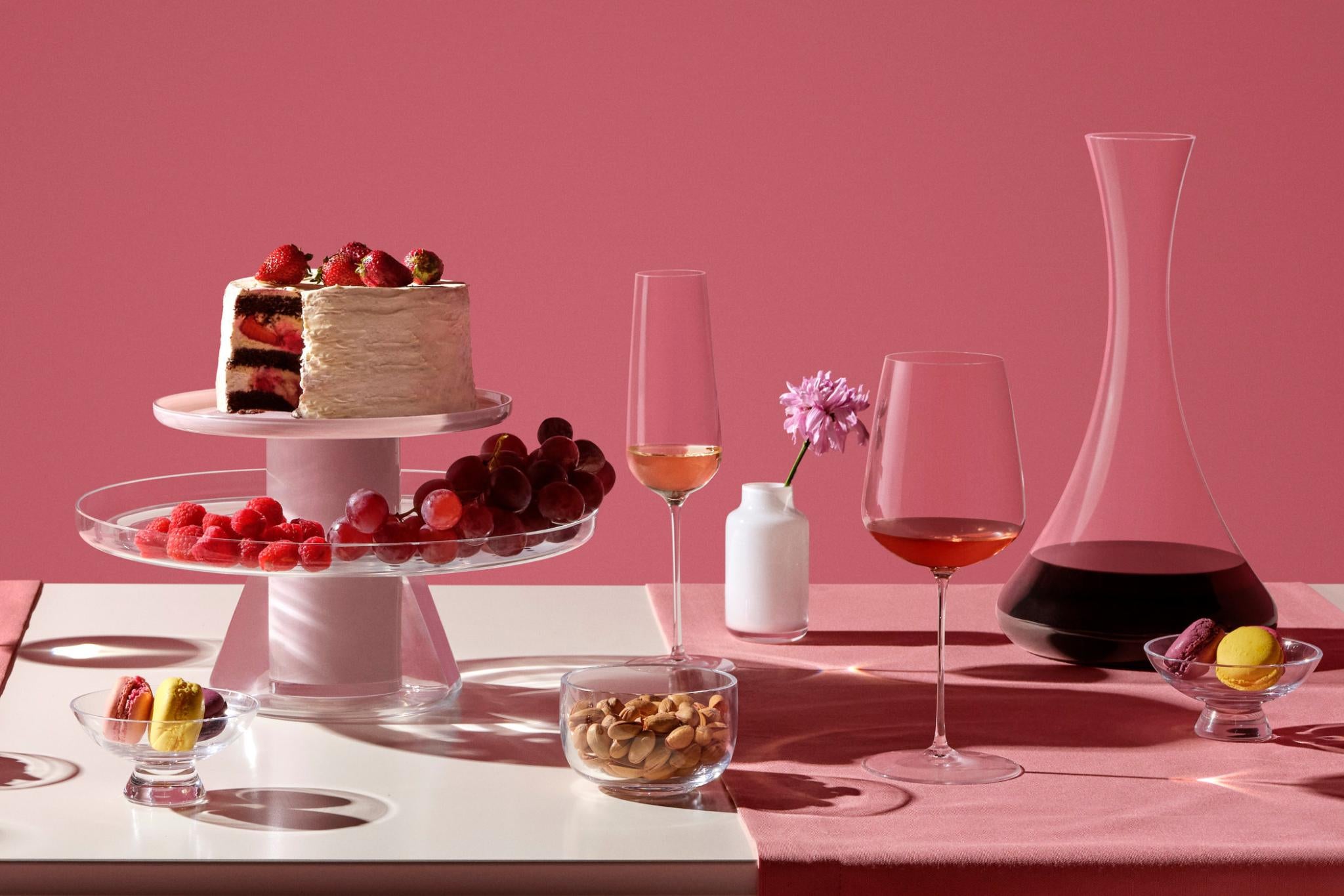 A NUDE Bloom cake stand, Silhouette serving bowl, Malt bowl, Stem Zero flute and wine glass, mini Magnolia vase and Jazz decanter styled on a pink celebration table.