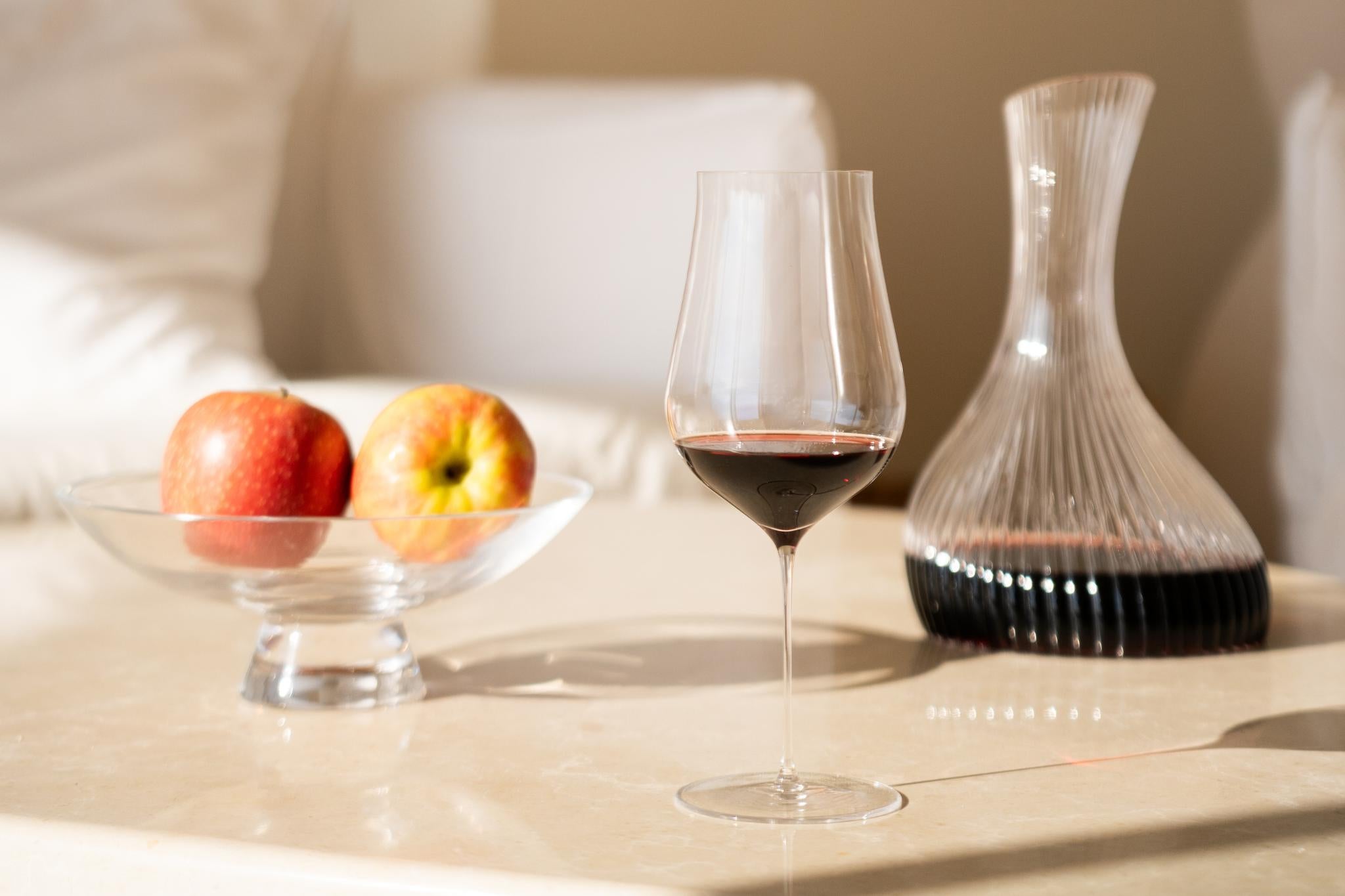 NUDE Ghost Zero Tulip Red Wine Glass with a Vini carafe and Silhouette bowl on a sunlit table