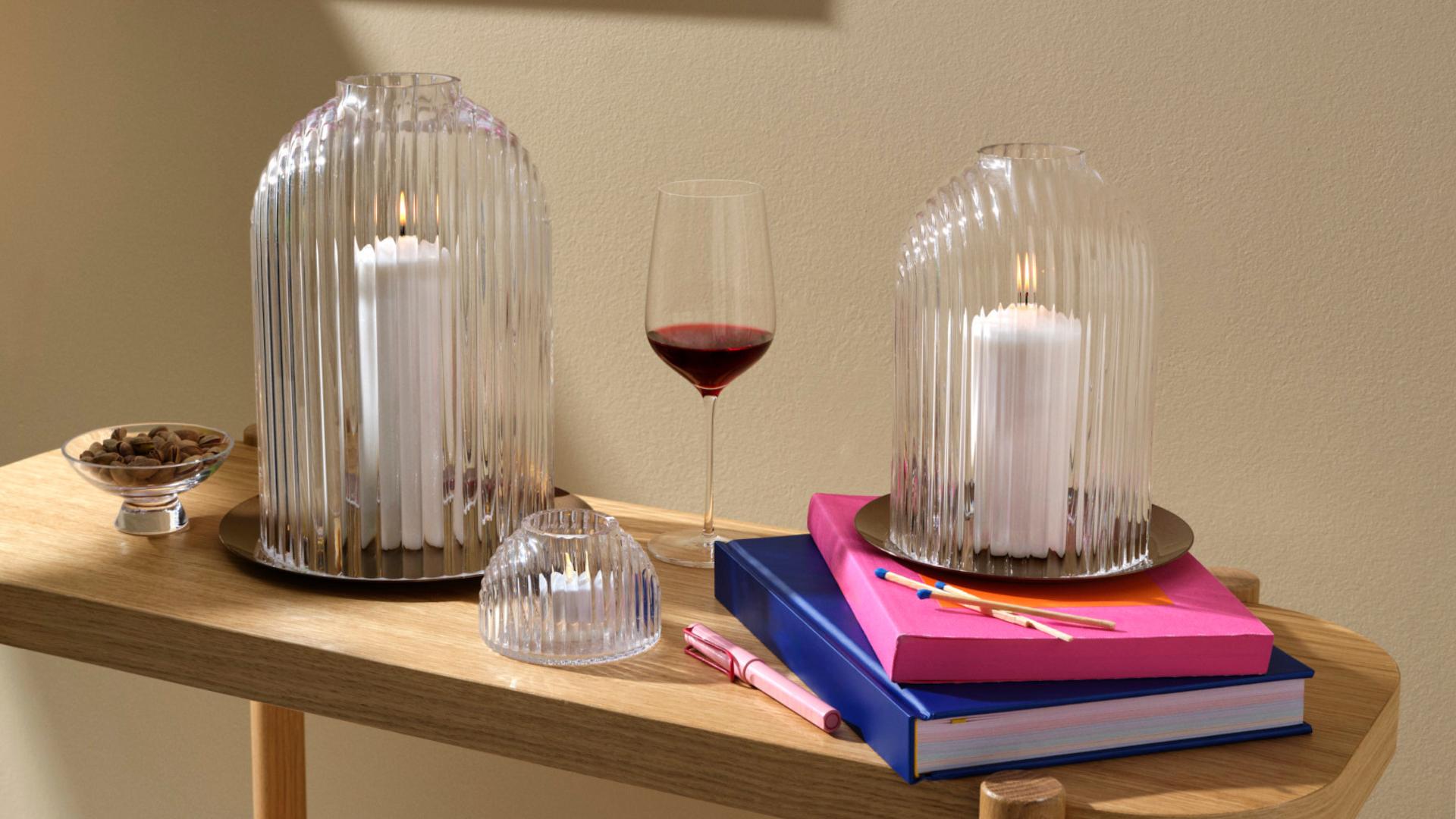 NUDE Ilo candleholders in two sizes with votive tealight holder and Stem Zero wine glass styled on oak console with colourful books