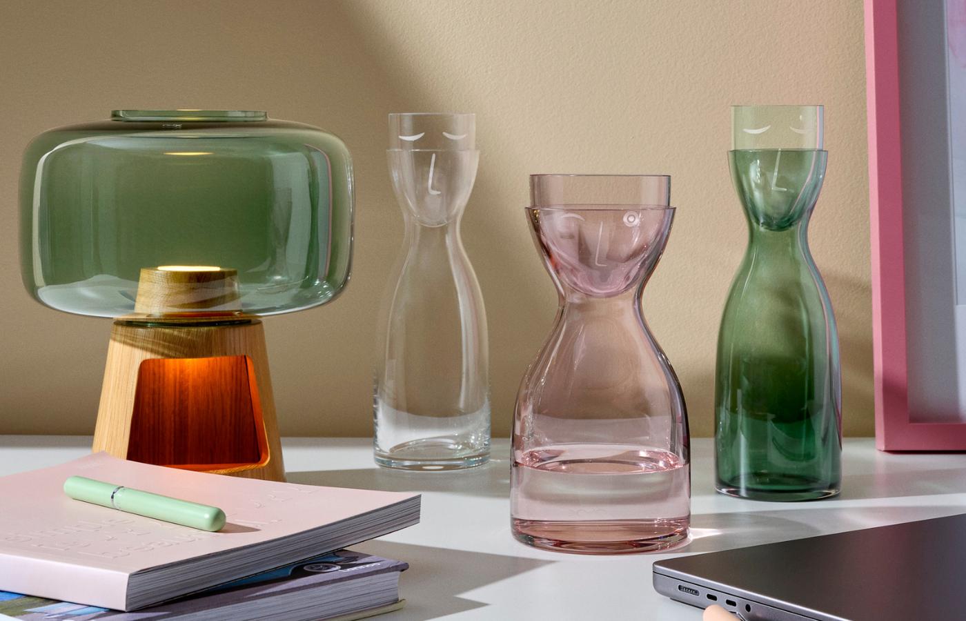 NUDE Mr & Mrs Water Carafes in green, pink and clear on a desk with NUDE's Tree Lamp with Glass and Oak Base