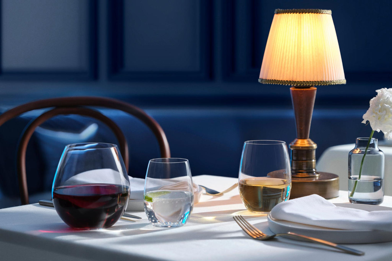 NUDE Pure stemless wine and water glasses with a Magnolia vase on a candlelit restaurant table