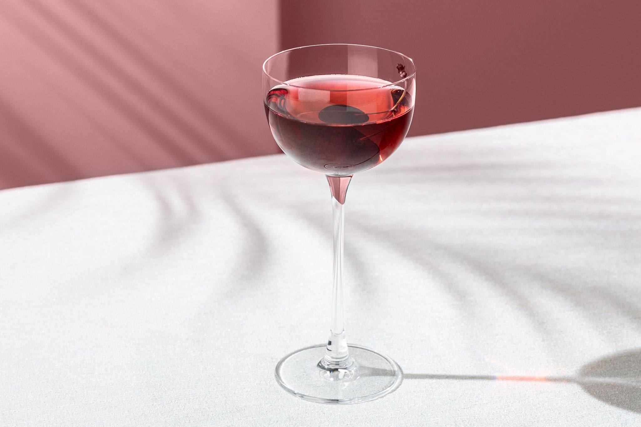 NUDE Savage Pony Glass with a red cocktail on a blush backdrop.