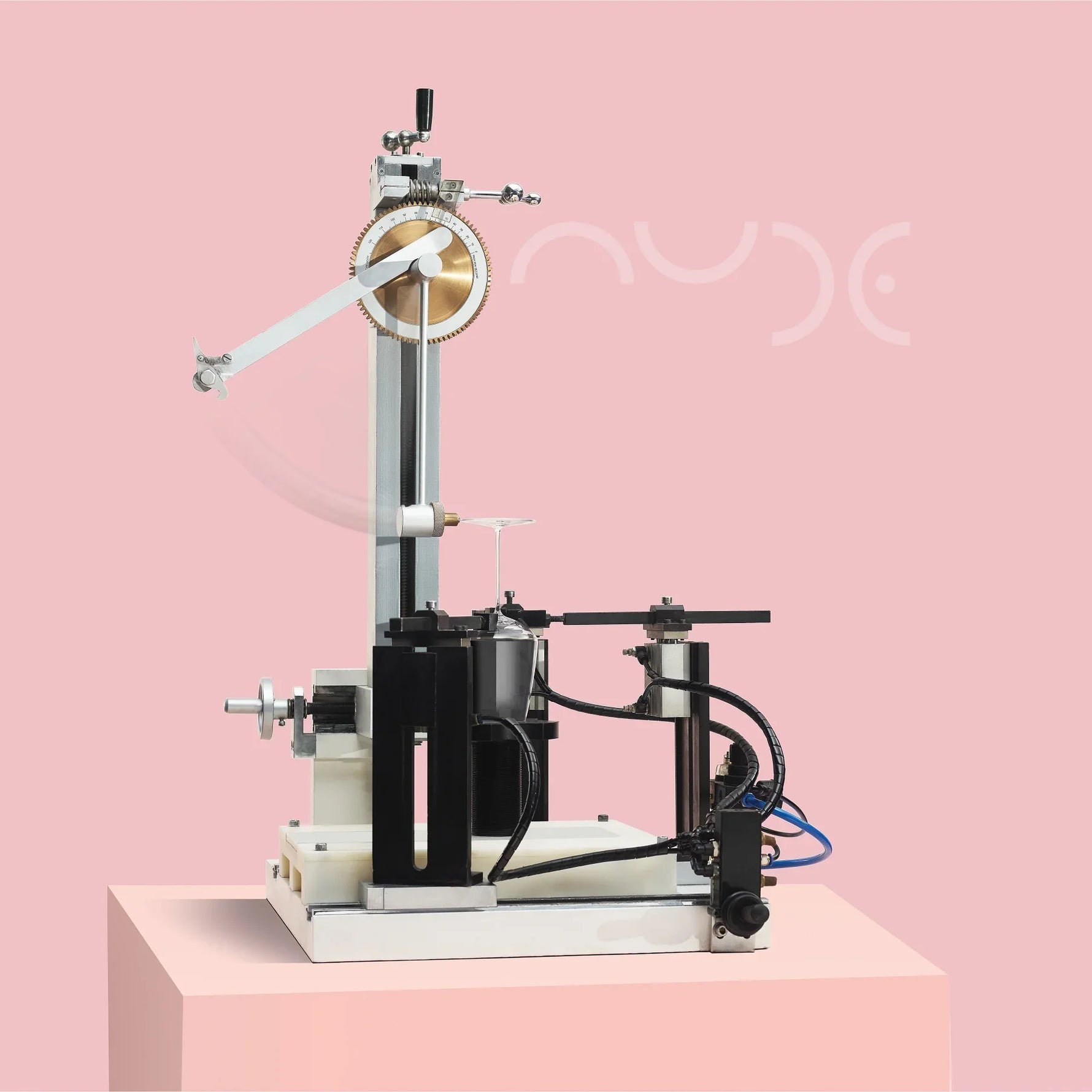 Mechanical device on a pink platform with 'NUDE' branding in the background