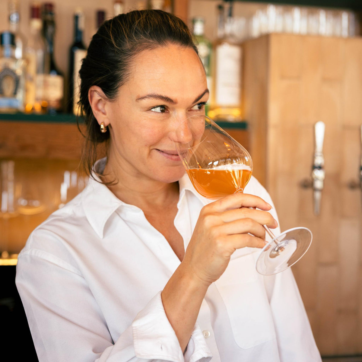 Honey Spencer holding a glass of orange wine at the bar at Sune