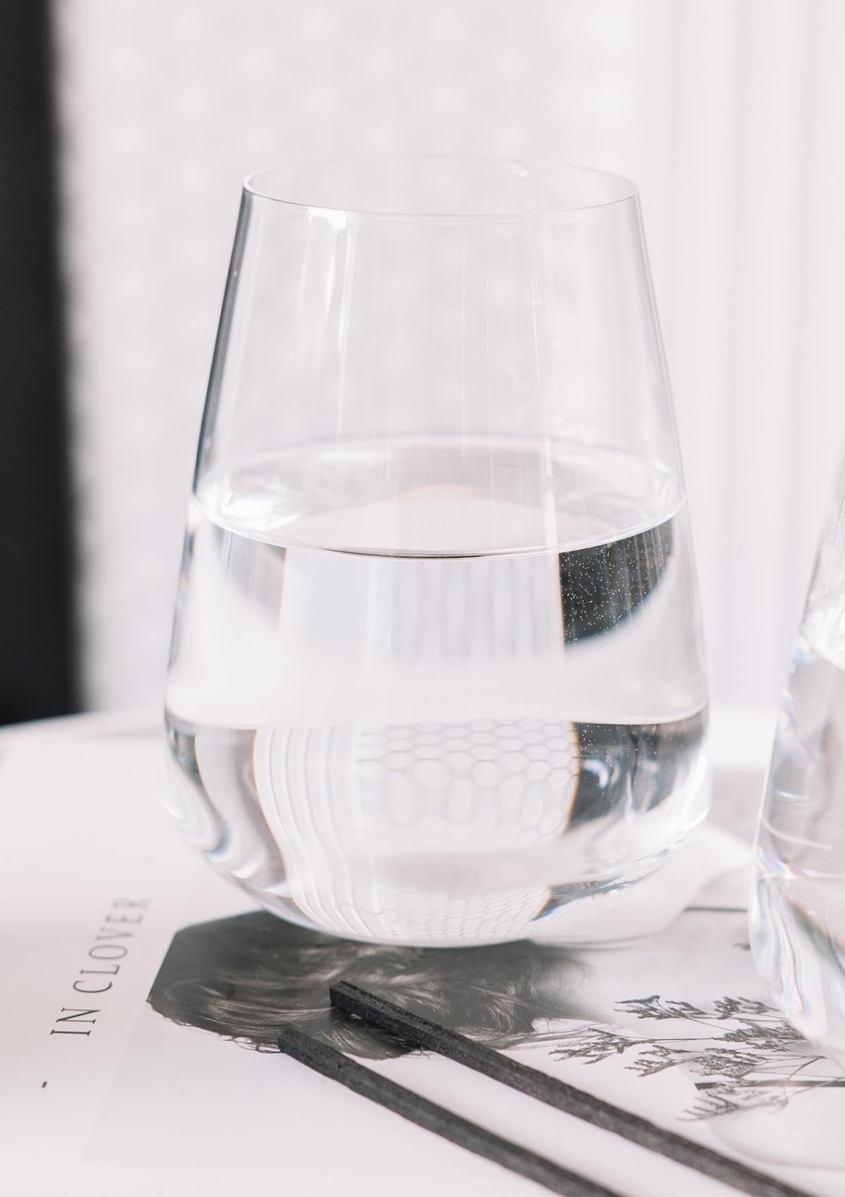 A NUDE Stem Zero Vertigo Water Glass filled with water on a styled table setting
