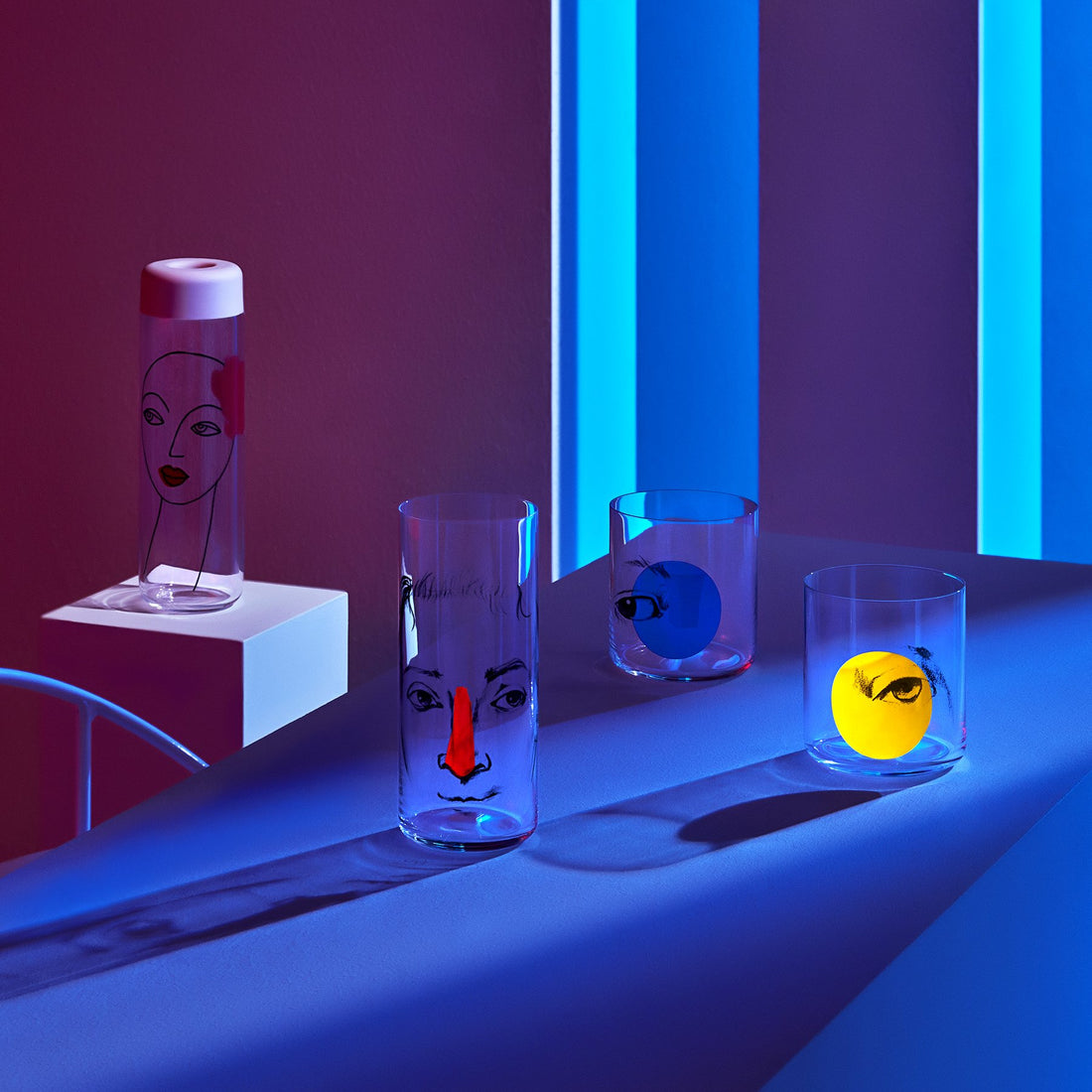 Lifestyle image of NUDE Rock & Pop glass collection with jug, highball glass and whisky glass in light neon environment