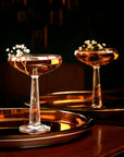 NUDE Big Top Coupe glass with linear patterned stem with elegant cocktail presented on a bar