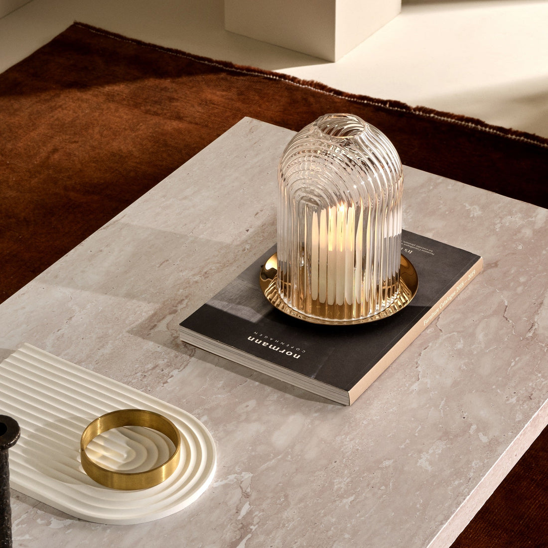 Lead-free crystal candle holder Ilo in small, a dome shaped candle holder with rippled glass effect, with candle presented on a table with some books and a small rippled tray in a dome shape